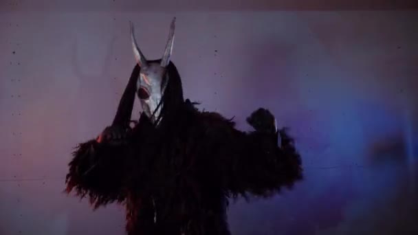 魔鬼怪物跳舞 一个戴着可怕面具的神秘男人在黑暗的工作室里这个男人穿着一件黑色外套 头上戴着一副有角的面具 来自太空的外星人可怕的事 — 图库视频影像