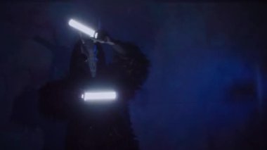 Şeytan canavar elinde RGB çubuklarıyla dans ediyor. Karanlık bir stüdyoda maskeli gizemli bir adam. Adam siyah bir ceket ve boynuzlu bir maske giymiş. Uzaylı uzaylı. Korkunç.,