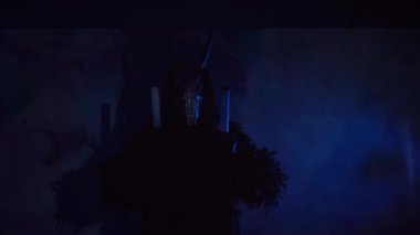 Şeytan canavar elinde RGB çubuklarıyla dans ediyor. Karanlık bir stüdyoda maskeli gizemli bir adam. Adam siyah bir ceket ve boynuzlu bir maske giymiş. Uzaylı uzaylı. Korkunç.,
