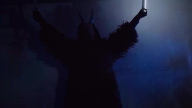 Şeytan canavar elinde RGB çubuklarıyla dans ediyor. Karanlık bir stüdyoda maskeli gizemli bir adam. Adam siyah bir ceket ve boynuzlu bir maske giymiş. Uzaylı uzaylı. Korkunç.,