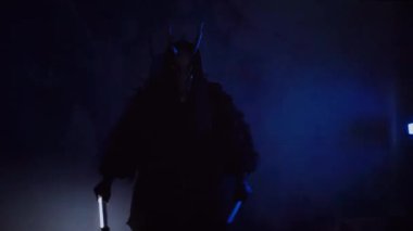 Şeytan canavar elinde RGB çubuklarıyla dans ediyor. Karanlık bir stüdyoda maskeli gizemli bir adam. Adam siyah bir ceket ve boynuzlu bir maske giymiş. Uzaylı uzaylı. Korkunç.,