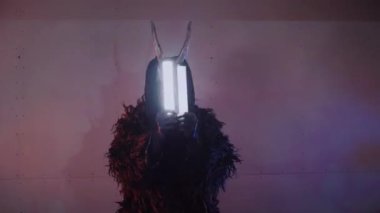 Şeytan canavar elinde RGB çubuklarıyla dans ediyor. Karanlık bir stüdyoda maskeli gizemli bir adam. Adam siyah bir ceket ve boynuzlu bir maske giymiş. Uzaylı uzaylı. Korkunç.,