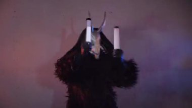 Şeytan canavar elinde RGB çubuklarıyla dans ediyor. Karanlık bir stüdyoda maskeli gizemli bir adam. Adam siyah bir ceket ve boynuzlu bir maske giymiş. Uzaylı uzaylı. Korkunç.,