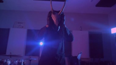 Şeytan canavar dans ediyor. Karanlık bir stüdyoda maskeli gizemli bir adam. Adam siyah bir ceket ve boynuzlu bir maske giymiş. Uzaylı uzaylı. Korkunç.,