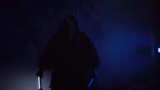 魔鬼带着Rgb跳舞 手里拿着棍子 一个戴着可怕面具的神秘男人在黑暗的工作室里这个男人穿着一件黑色外套 头上戴着一副有角的面具 来自太空的外星人可怕的事 — 图库视频影像