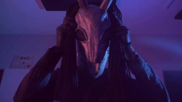 悪魔モンスターが踊る 暗いスタジオで恐ろしい仮面の神秘的な男 男は黒いコートと頭に角のあるマスクを着ている 宇宙からのエイリアン ホラー — ストック動画