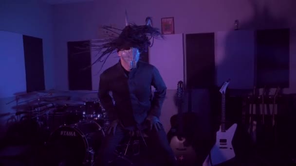 悪魔モンスターが踊る 暗いスタジオで恐ろしい仮面の神秘的な男 男は黒いコートと頭に角のあるマスクを着ている 宇宙からのエイリアン ホラー — ストック動画