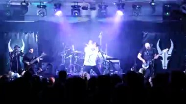 Kulüpte rock konseri. Gece kulübü partisi. Rock grubu rock festivalinde çalıyor. Konserdeki bir grup insan heyecanla ellerini kaldırdı. Kollarını kaldırıp canlı müziğin keyfini çıkarıyorlar. Taraftarlar dans ediyor ve konserde coşku gösteriyorlar.