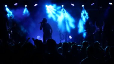 Kulüpte rock konseri. Gece kulübü partisi. Rock grubu rock festivalinde çalıyor. Konserdeki bir grup insan heyecanla ellerini kaldırdı. Kollarını kaldırıp canlı müziğin keyfini çıkarıyorlar. Taraftarlar dans ediyor ve konserde coşku gösteriyorlar.