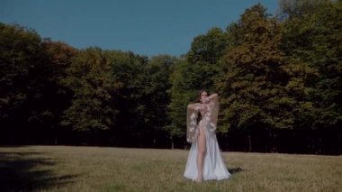 Ormanda göbek dansı yapan bir kız. Doğulu dansı. Ağır çekim. Sütyen ve etek içinde güzel bir dansçı. Beyaz göbek dansı kostümü giymiş bir kadın. Akan hareketlerle sahada poz veriyor. Beyaz giyinmiş bir kadın, güzel bir açık havada göbek dansı hareketleri sergiliyor.