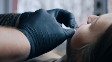 Dudak büyütme prosedürü. Yaklaş, dişi dudak. Erkek cerrah dikkatli ve yavaşça kadının dudaklarına hyaluronik asit enjekte ediyor. Güzellik iğneleri. Estetik ameliyat.