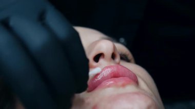 Dudak büyütme prosedürü. Yaklaş, dişi dudak. Erkek cerrah dikkatli ve yavaşça kadının dudaklarına hyaluronik asit enjekte ediyor. Güzellik iğneleri. Estetik ameliyat.