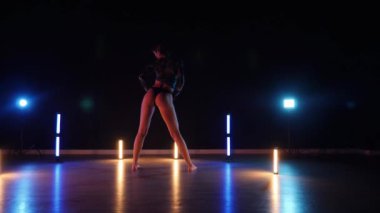 Baştan çıkarıcı dans eden seksi kadın. Erotik bir dansçı kız. Twerk, yüksek topuklu ayakkabı, striptiz. Neon ışıklarla çevrili yerde yatan bir kadın. Canlı neon ışıklarının altında yerde dinlenen bir kadın. Bikinili kadın çömelme egzersizi yapıyor. 