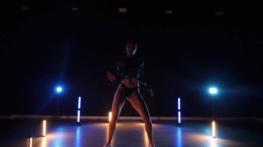 Baştan çıkarıcı dans eden seksi kadın. Erotik bir dansçı kız. Twerk, yüksek topuklu ayakkabı, striptiz. Neon ışıklarla çevrili yerde yatan bir kadın. Canlı neon ışıklarının altında yerde dinlenen bir kadın. Bikinili kadın çömelme egzersizi yapıyor. 