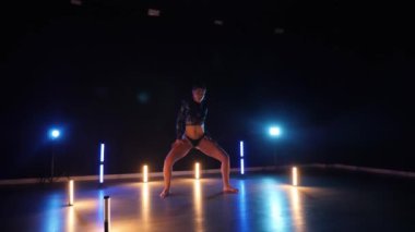 Baştan çıkarıcı dans eden seksi kadın. Erotik bir dansçı kız. Twerk, yüksek topuklu ayakkabı, striptiz. Neon ışıklarla çevrili yerde yatan bir kadın. Canlı neon ışıklarının altında yerde dinlenen bir kadın. Bikinili kadın çömelme egzersizi yapıyor. 