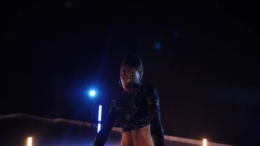 Baştan çıkarıcı dans eden seksi kadın. Erotik bir dansçı kız. Twerk, yüksek topuklu ayakkabı, striptiz. Neon ışıklarla çevrili yerde yatan bir kadın. Canlı neon ışıklarının altında yerde dinlenen bir kadın. Bikinili kadın çömelme egzersizi yapıyor. 