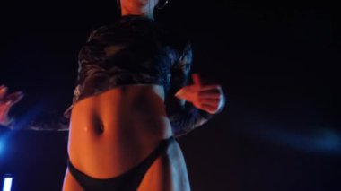 Baştan çıkarıcı dans eden seksi kadın. Erotik bir dansçı kız. Twerk, yüksek topuklu ayakkabı, striptiz. Neon ışıklarla çevrili yerde yatan bir kadın. Canlı neon ışıklarının altında yerde dinlenen bir kadın. Bikinili kadın çömelme egzersizi yapıyor. 