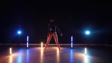 Baştan çıkarıcı dans eden seksi kadın. Erotik bir dansçı kız. Twerk, yüksek topuklu ayakkabı, striptiz. Neon ışıklarla çevrili yerde yatan bir kadın. Canlı neon ışıklarının altında yerde dinlenen bir kadın. Bikinili kadın çömelme egzersizi yapıyor. 