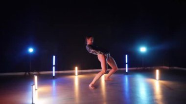 Baştan çıkarıcı dans eden seksi kadın. Erotik bir dansçı kız. Twerk, yüksek topuklu ayakkabı, striptiz. Neon ışıklarla çevrili yerde yatan bir kadın. Canlı neon ışıklarının altında yerde dinlenen bir kadın. Bikinili kadın çömelme egzersizi yapıyor. 