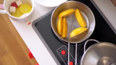 Ahşap mutfak setiyle yemek yapıyormuş gibi yapan küçük bir kız. Minyatür ahşap soba ve tencere ile yaratıcı bir oyun. Mutlu bir çocukla ahşap mutfak seti. Genç kız yemek yaparken eğleniyor. Çocukların mutfağında küçük bir kız oynuyor.. 