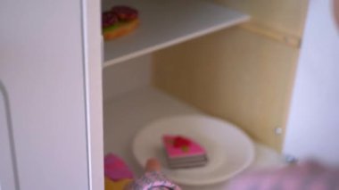 Ahşap mutfak setiyle yemek yapıyormuş gibi yapan küçük bir kız. Minyatür ahşap soba ve tencere ile yaratıcı bir oyun. Mutlu bir çocukla ahşap mutfak seti. Genç kız yemek yaparken eğleniyor. Çocukların mutfağında küçük bir kız oynuyor.. 