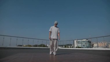 Adam evin çatısında serin kanlılıkla break dans yapıyor. Bir adam enerjik bir atletik dans eder. Adam çatıda dans ederken hiç zorlanmadan break dans yapıyor. Şehir dansçısı çatıda hünerlerini gösteriyor. Breakdansçı yeteneklerini şehrin üzerinde sergiliyor.. 