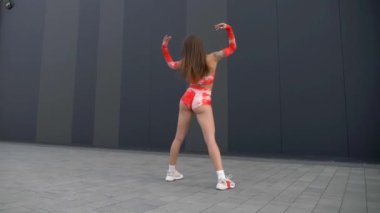 Kırmızı ve turuncu bikinili kadın twerking. Bikinili kadın enerjik bir şekilde dans ediyor. Kadın canlı bikinisiyle dans figürlerini gösteriyor. Kırmızı ve turuncu bikinili bir kadın dans ediyor. Canlı bikinili kadın güneşin altında dans ediyor. Güzellik zarifçe hareket ediyor