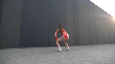 Kırmızı ve turuncu bikinili kadın twerking. Bikinili kadın enerjik bir şekilde dans ediyor. Kadın canlı bikinisiyle dans figürlerini gösteriyor. Kırmızı ve turuncu bikinili bir kadın dans ediyor. Canlı bikinili kadın güneşin altında dans ediyor. Güzellik zarifçe hareket ediyor