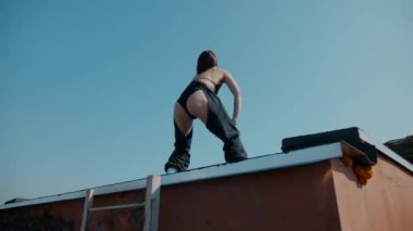 Mayolu bir kız çatıda twerk yapıyor. Ganimet dansı, popo sallama, Twerk, Yüksek Topuklar, Hip Hop. Erotik dans eden kadın. Genç kız enerjik bir şekilde seksi bir dans ediyor. Genç bir kız çıplak kalçalarıyla seksi dans eder.. 