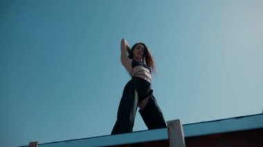 Mayolu bir kız çatıda twerk yapıyor. Ganimet dansı, popo sallama, Twerk, Yüksek Topuklar, Hip Hop. Erotik dans eden kadın. Genç kız enerjik bir şekilde seksi bir dans ediyor. Genç bir kız çıplak kalçalarıyla seksi dans eder.. 