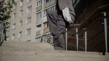 Kız şehir caddesinde serin kanlı hip-hop dansı yapıyor. Bir dansçı bir şehir evinin yakınında dans eder. Gri gömlekli kadın merdivenlerde numaralar yapıyor. Merdivenlerde gösteriş yapan kız. Merdivenlerde gri tişörtlü bir sokak sanatçısı. Gri gömlekli bir kadının merdiven numaraları..