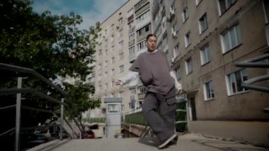 Kız şehir caddesinde serin kanlı hip-hop dansı yapıyor. Bir dansçı bir şehir evinin yakınında dans eder. Gri gömlekli kadın merdivenlerde numaralar yapıyor. Merdivenlerde gösteriş yapan kız. Merdivenlerde gri tişörtlü bir sokak sanatçısı. Gri gömlekli bir kadının merdiven numaraları..