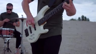 Adam çölde bas gitar çalmakta çok iyi. Çölde kumların üzerinde bir müzik grubu çalıyor. Profesyonel müzisyen..