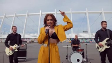 Seksi kız bir grupta serin şarkı söyler. Müzik grubu stadyumun arka planında çaldı. Şehir merkezinde güzel bir kadın vokalist şarkı söyler. Sütyenli bir model bir grupta şarkı söyler..