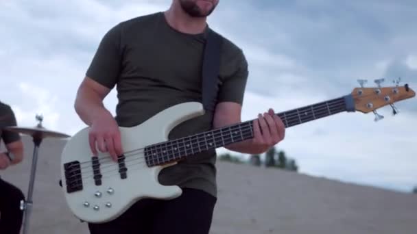 那家伙在沙漠里弹低音吉他很酷 一个乐队在沙漠的沙滩上演奏 专业音乐家 — 图库视频影像
