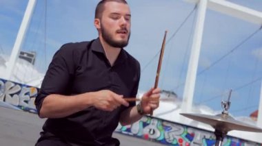 Adam soğukkanlılıkla davul çalıyor. Bir müzik grubu stadyumun arka planına karşı meydanda çalıyor..