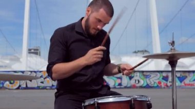 Adam soğukkanlılıkla davul çalıyor. Bir müzik grubu stadyumun arka planına karşı meydanda çalıyor..