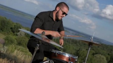 Güneşli bir günde bir grup dışarıda canlı çalar. Kadın bir grupta güzel şarkı söylüyor. Grup doğada çalıyor. Basçı, gitarist, davulcu, profesyonel, konser. Güzel manzara.