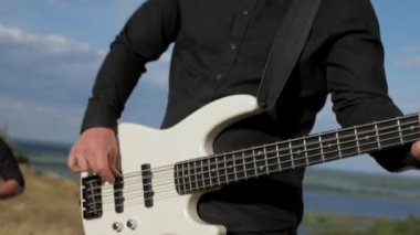 Güneşli bir günde bir grup dışarıda canlı çalar. Kadın bir grupta güzel şarkı söylüyor. Grup doğada çalıyor. Basçı, gitarist, davulcu, profesyonel, konser. Güzel manzara.