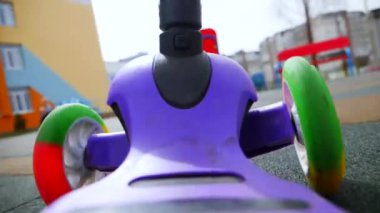 Çocuk parkında bir scooter sürüyor. Scooter 'a binen ilk kişinin görüntüsü. Ağır çekim. Bir çocuk lunaparkta scooter kullanıyor..