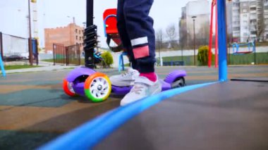 Küçük bir kız scooter kullanıyor. Çocuk parkında bir scooter sürüyor. Yavaş hareket. Bir çocuk lunaparkta scooter kullanıyor..