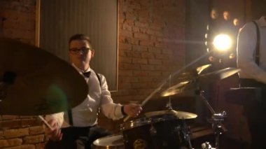 Bir erkek davulcu stüdyoda davul çalar. Müzik grubu restoranda çalar. Gece romantik bir ışıktır. Jazz, Blues, Funk Retro stüdyosu, tuğla iç mekan.