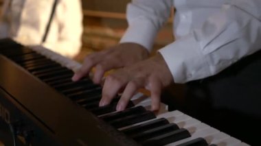 Adam stüdyoda klavye sentezleyicisini çalıyor. Elektrikli piyano. İplerin ve pulların makro çekimi. Müzik grubu restoranda çalar. Gece romantik bir ışıktır. Jazz, Blues, Funk Retro stüdyosu, tuğla iç mekan.