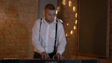 Adam stüdyoda klavye sentezleyicisini çalıyor. Elektrikli piyano. İplerin ve pulların makro çekimi. Müzik grubu restoranda çalar. Gece romantik bir ışıktır. Jazz, Blues, Funk Retro stüdyosu, tuğla iç mekan.