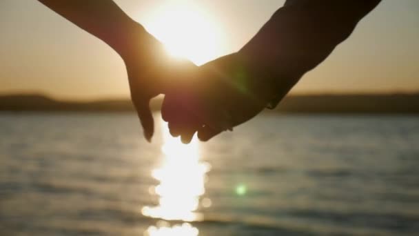 サンセットでキスをするカップルのシルエット 海で花嫁を愛する 恋人のキス 日没時に水に抱かれる花嫁とグルーミング 新婚夫婦が水辺で夕暮れに立っている 水による日没に対するシルエット — ストック動画