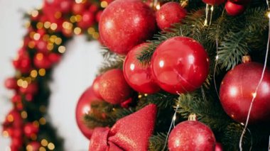 Geleneksel Noel ağacı kırmızı süslemelerle süslenmiş. Güzel dekore edilmiş Noel ağacı olan şenlik odası. Kırmızı takılar bir tatil ağacına renk katıyor. Kırmızıyla süslenmiş klasik bir Noel ağacıyla samimi bir ortam. Zarif dekorasyonlar 