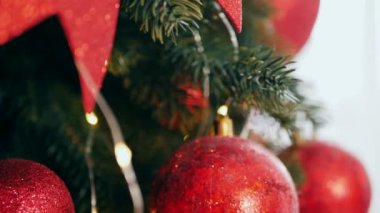 Geleneksel Noel ağacı kırmızı süslemelerle süslenmiş. Güzel dekore edilmiş Noel ağacı olan şenlik odası. Kırmızı takılar bir tatil ağacına renk katıyor. Kırmızıyla süslenmiş klasik bir Noel ağacıyla samimi bir ortam. Zarif dekorasyonlar 