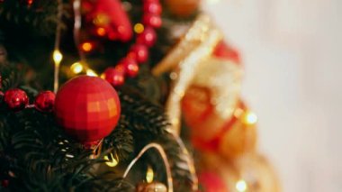 Geleneksel Noel ağacı kırmızı süslemelerle süslenmiş. Güzel dekore edilmiş Noel ağacı olan şenlik odası. Kırmızı takılar bir tatil ağacına renk katıyor. Kırmızıyla süslenmiş klasik bir Noel ağacıyla samimi bir ortam. Zarif dekorasyonlar 