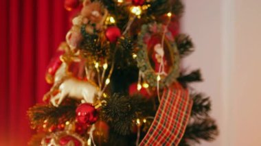 Geleneksel Noel ağacı kırmızı süslemelerle süslenmiş. Güzel dekore edilmiş Noel ağacı olan şenlik odası. Kırmızı takılar bir tatil ağacına renk katıyor. Kırmızıyla süslenmiş klasik bir Noel ağacıyla samimi bir ortam. Zarif dekorasyonlar 