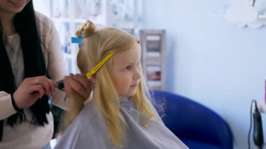 Küçük kız bir çocuk berberinde saç tıraşı oluyor. Genç bir kız, saçını bir salonda kestirirken sakince oturur. Kuaför salonu ziyareti sırasında yüzünde gülümseme olan bir çocuk. Kuaförde saçını kestiren küçük bir kız. Çocuk kuaförü.